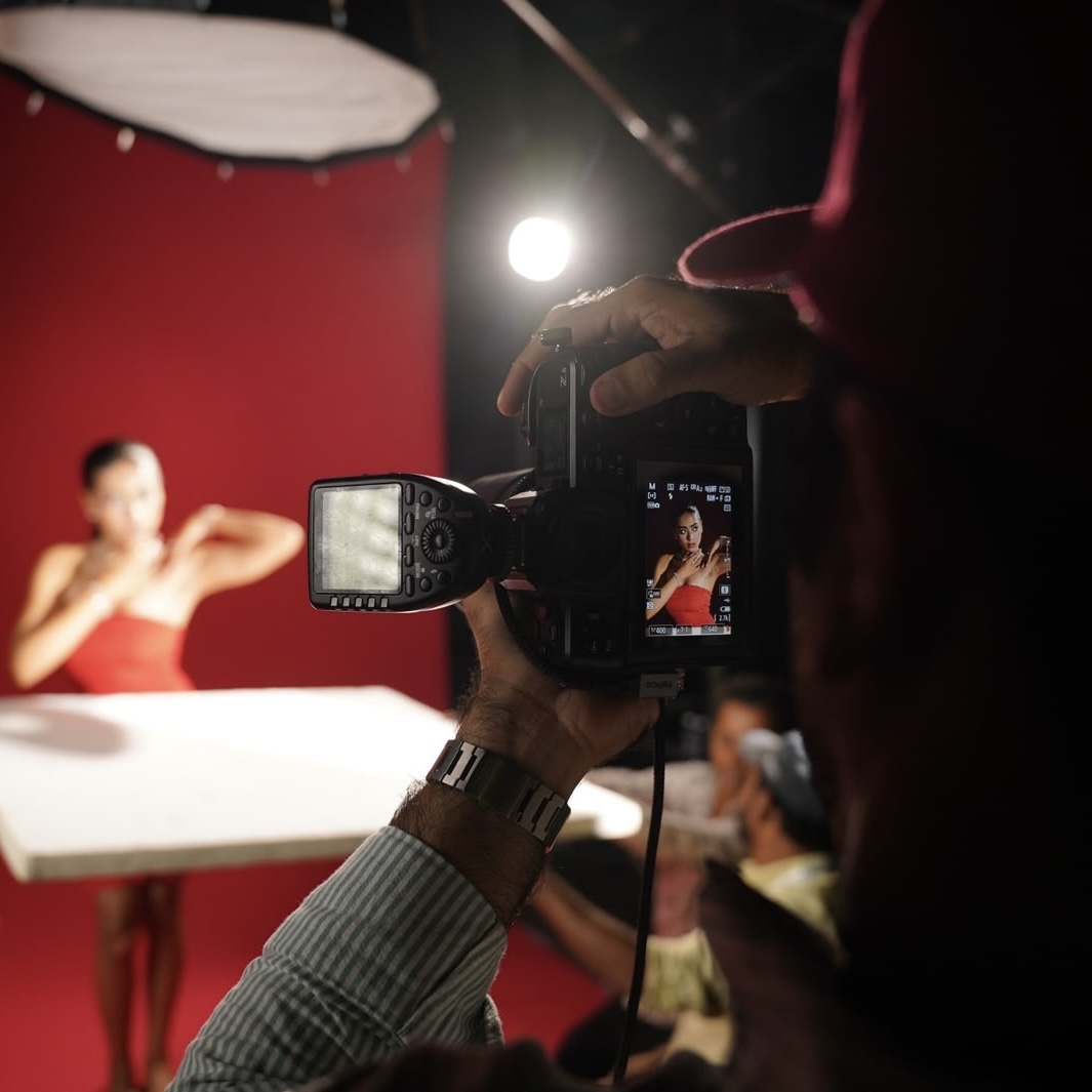 Campaign shoot seen through the camera viewfinder, talent in a red dress on set